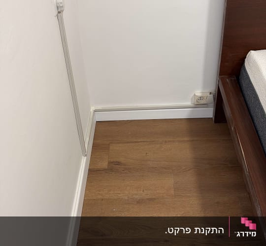 רצפת פרקט ליד מיטה וקיר לבן